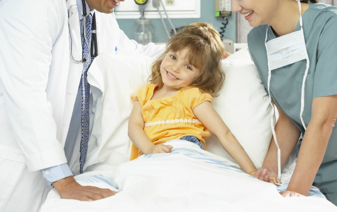 child_patient_smiling_hospital_bed_doctor_nurse_flanking_her
