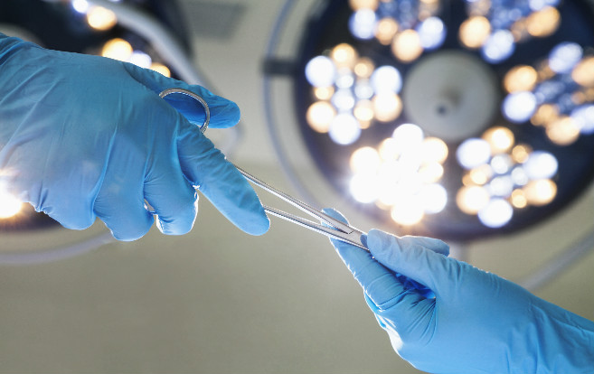 close_up_gloved_hands_passing_surgical_scissors_operating_room