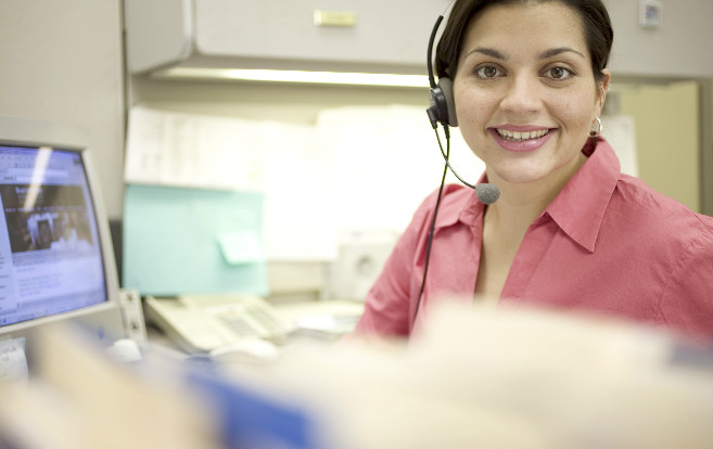 woman_smiling_phone_headset_computer_sitting_desk_files_recruiter